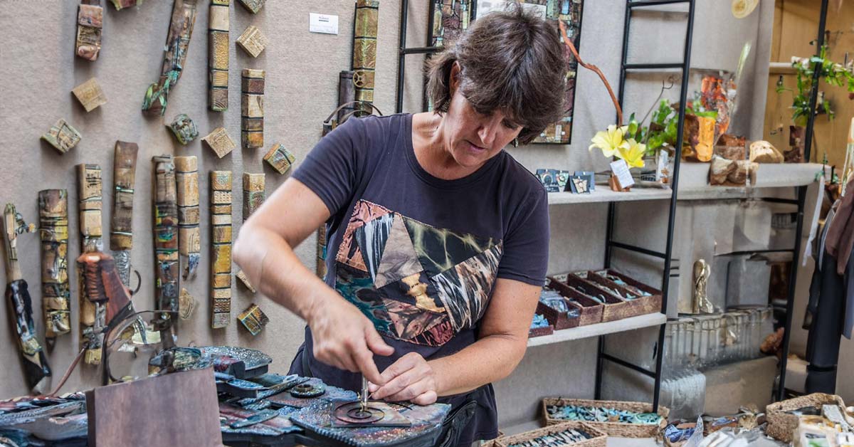 Ceramic artist, Courtney Fall Tomchik, working on one of her sculptural pieces while in her booth at a craft fair.