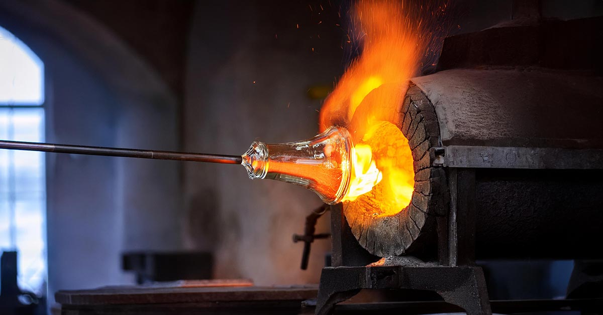 A fiery hot piece of soft glass emerging from a furnace at the end of a glass-maker's rod.